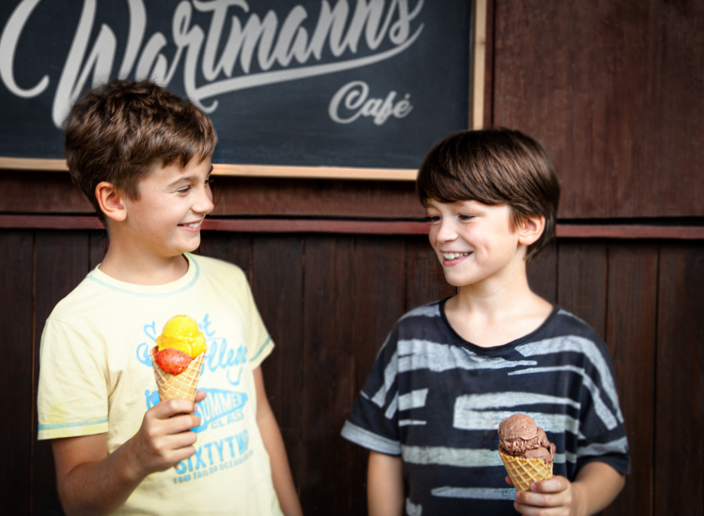 Zwei Jungs stehen vor den Wartmanns Café lächeln und essen Eis in Waffeln